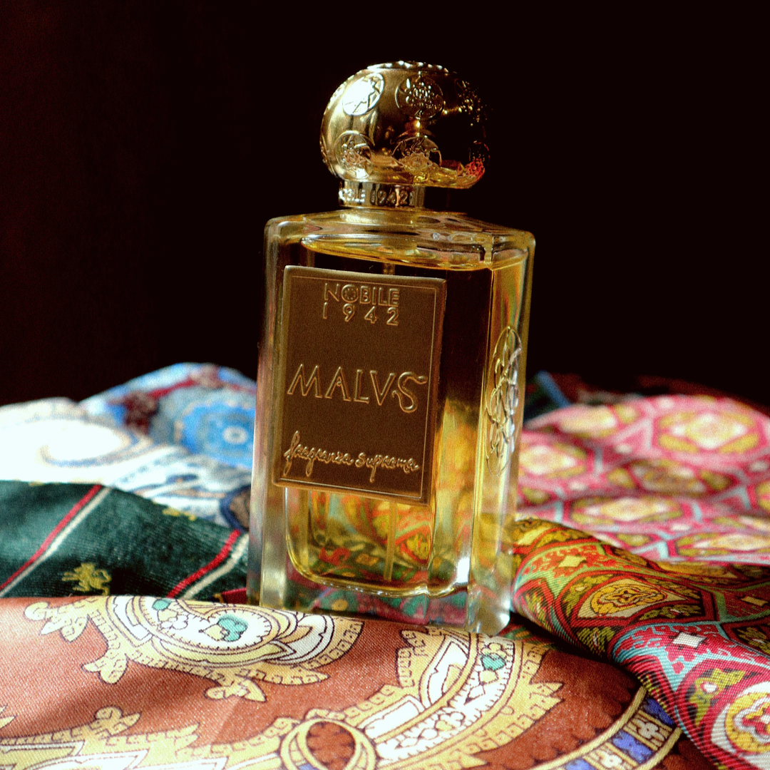 Perfume bottle labeled 'Malvs' on a decorative  paisley fabric background